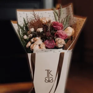 Tropical Elegance Bouquet featuring vibrant pink and purple roses, white lilies, and unique tropical greenery arranged in a contemporary vase.