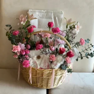 Pink flower bouquet in Sweet Beginnings Basket featuring baby essentials for newborn gift